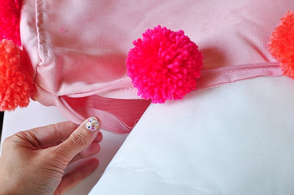 Instructions on how to make and add DIY Pom Poms to an Existing Pillow in your home.  It is much easier than you would think! Add a little fun texture to your pillows today. Delineate Your Dwelling #pompompillow #DIYpompompillow