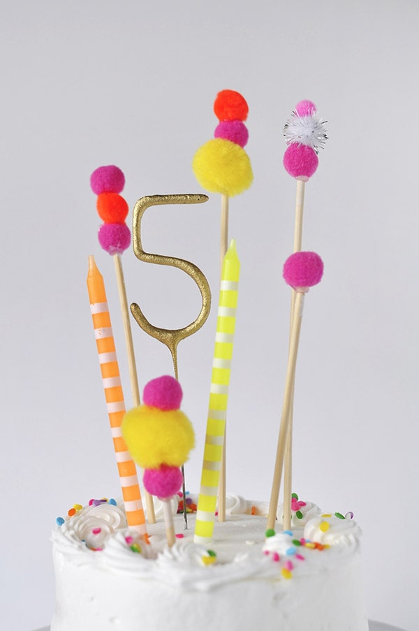 Adorable and simple, see how to create this Pom Pom Birthday Cake Topper for your next party!  Fun Banner Cake Toppers make celebrations so much more fun and they are easy to add to any dessert. Delineate Your Dwelling #pompombirthdaycake #pompomcaketopper #birthdaytopper #pompomcake