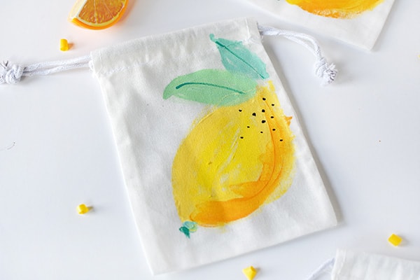 Learn how to paint fun refreshingly easy DIY Painted Lemon Bags! They are great to give as gift bags, teacher gifts or just told tasty treats. Perfect for summer fun. Delineate Your Dwelling #paintlemon #lemonbag #fruitcraft