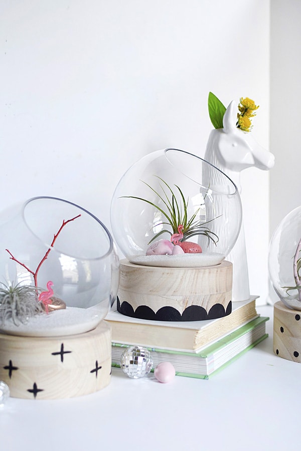 A modern take on a traditional plant terrarium! Painted Crosses, Scallops and Polka Dots add the perfect pattern to the wood base.  Learn how to create this trendy DIY using air plants, disco balls and mini flamingos. Delineate Your Dwelling #modernterrarium #airplantterrarium