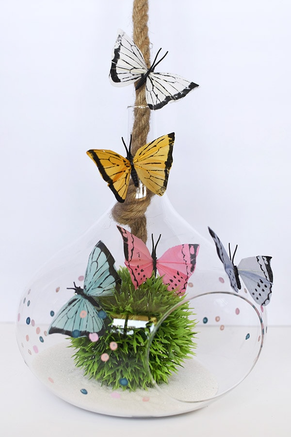 Learn how to make a DIY butterfly terrarium this Spring season!  Using colorful faux butterflies, gorgeous glass terrariums and some fun moss balls the sky is the limit to the fun you can have. Delineate Your Dwelling #DIYterrarium #butterflyterrarium