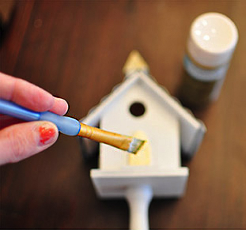 Painting gold details on birdhouse