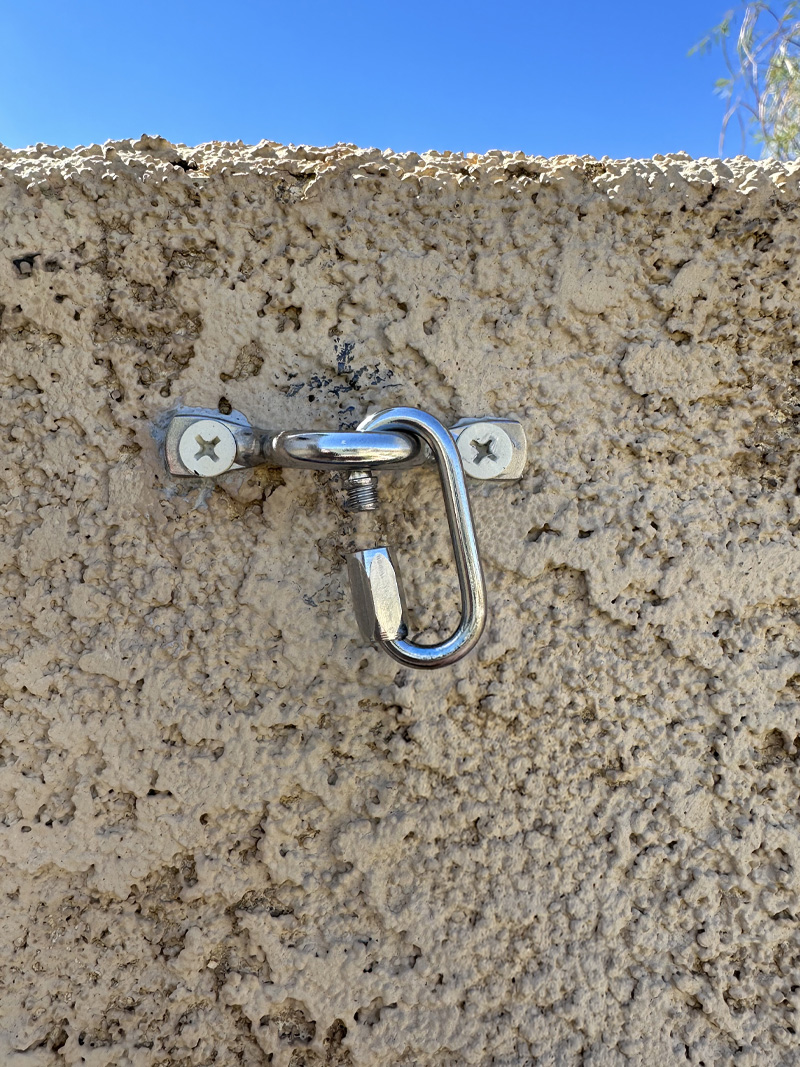 Waterproof caulk on stucco wall with a metal eyelet hook