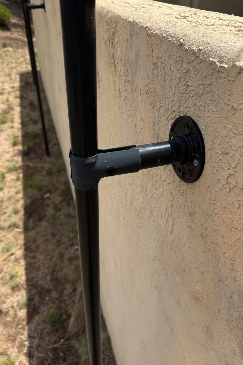 Black pole clamps on a stucco wall