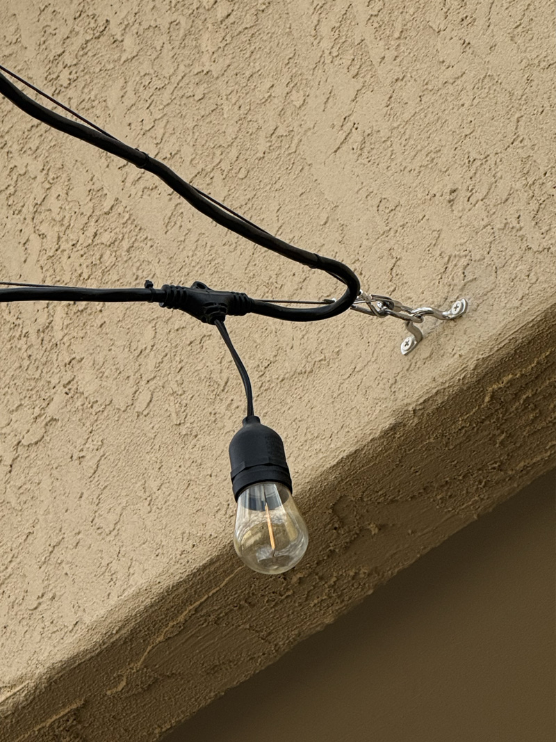 String light wire guide end attached to a stucco house