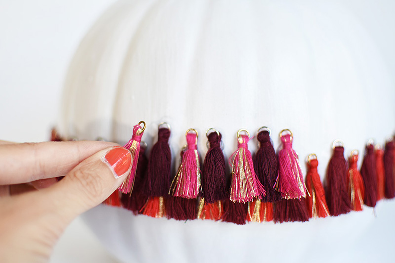 Adding pink tassels in a row to a white pumpkin