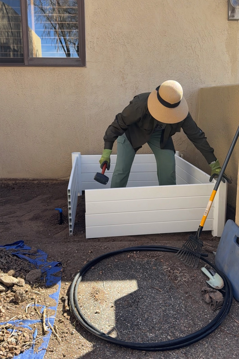 Reassembling white vinyl garden bed with a mallet hammer