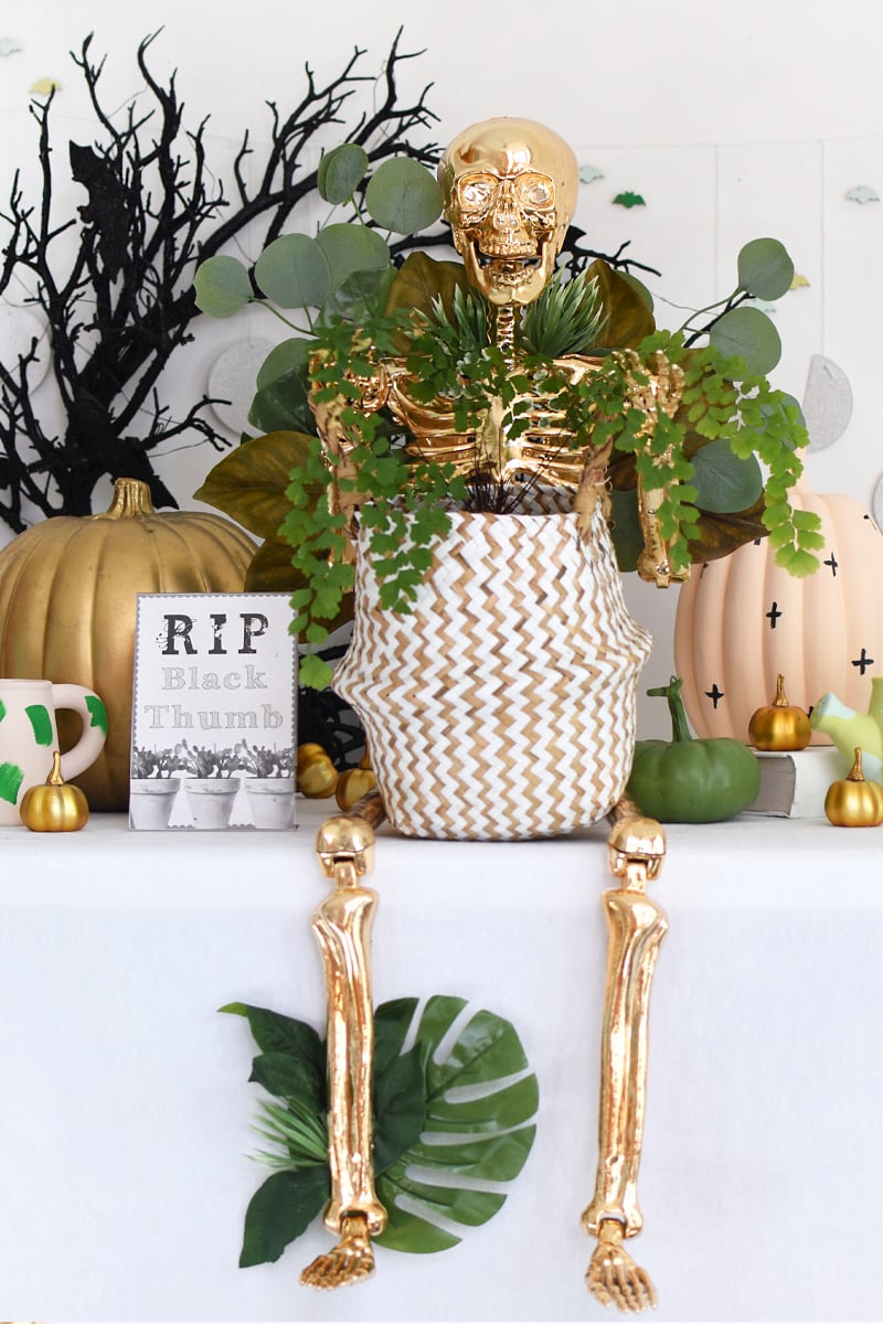 Gold skeleton holding a fern plant