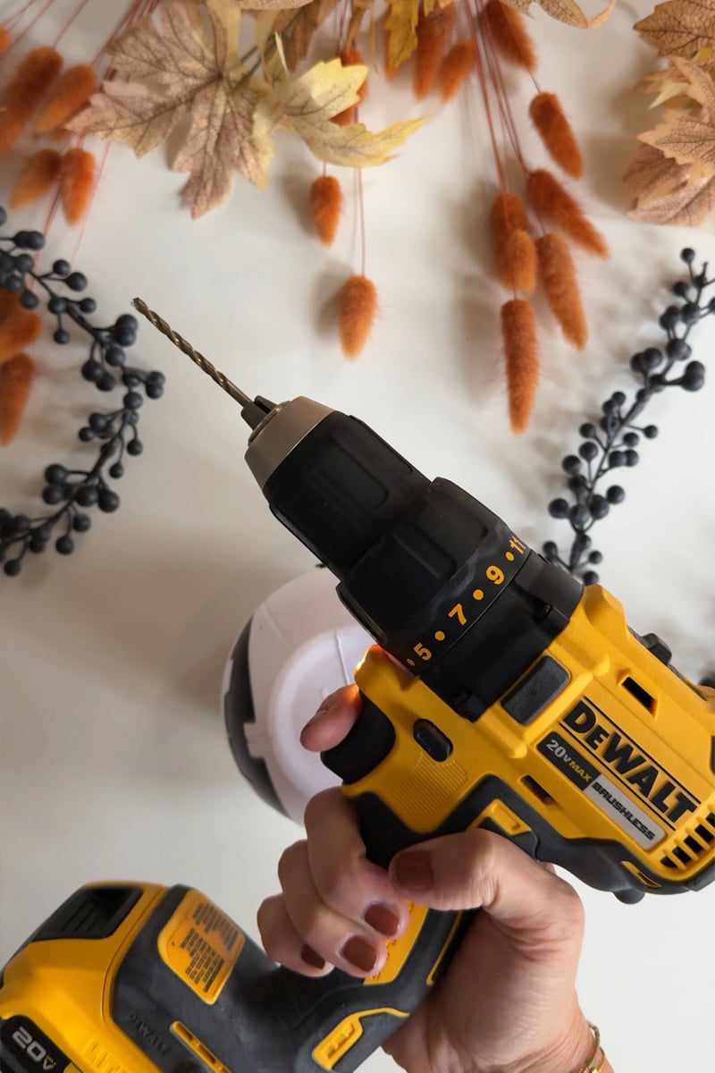 Cordless yellow electric drill surrounded by fall leaves