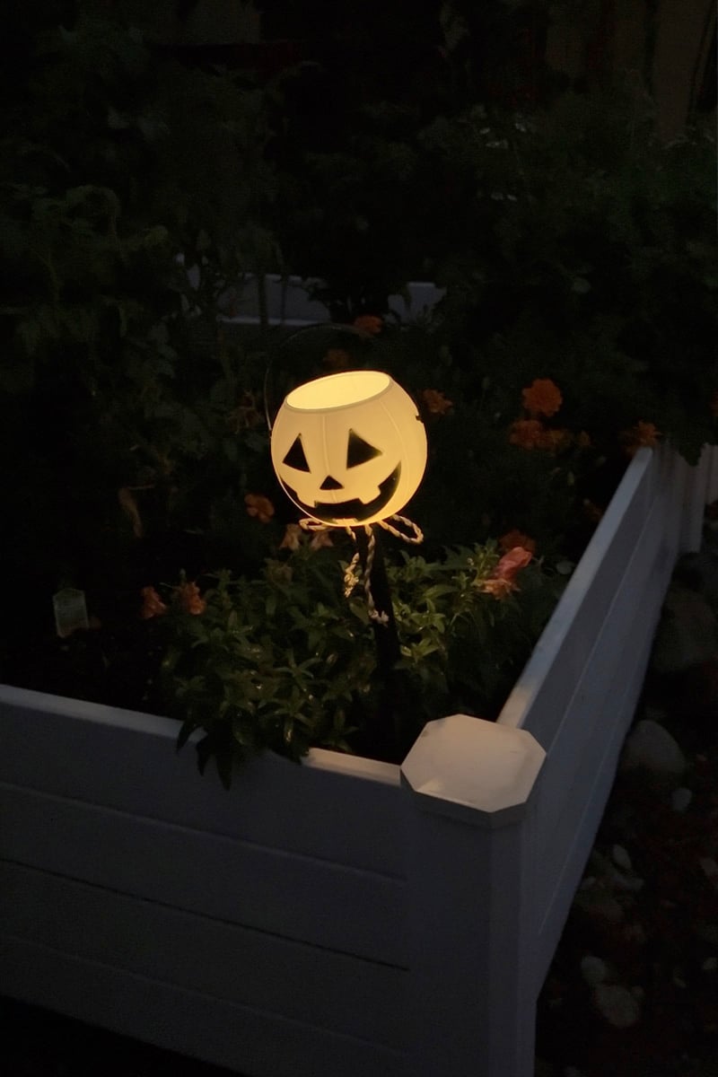 White glowing pumpkin light in a dark garden bed