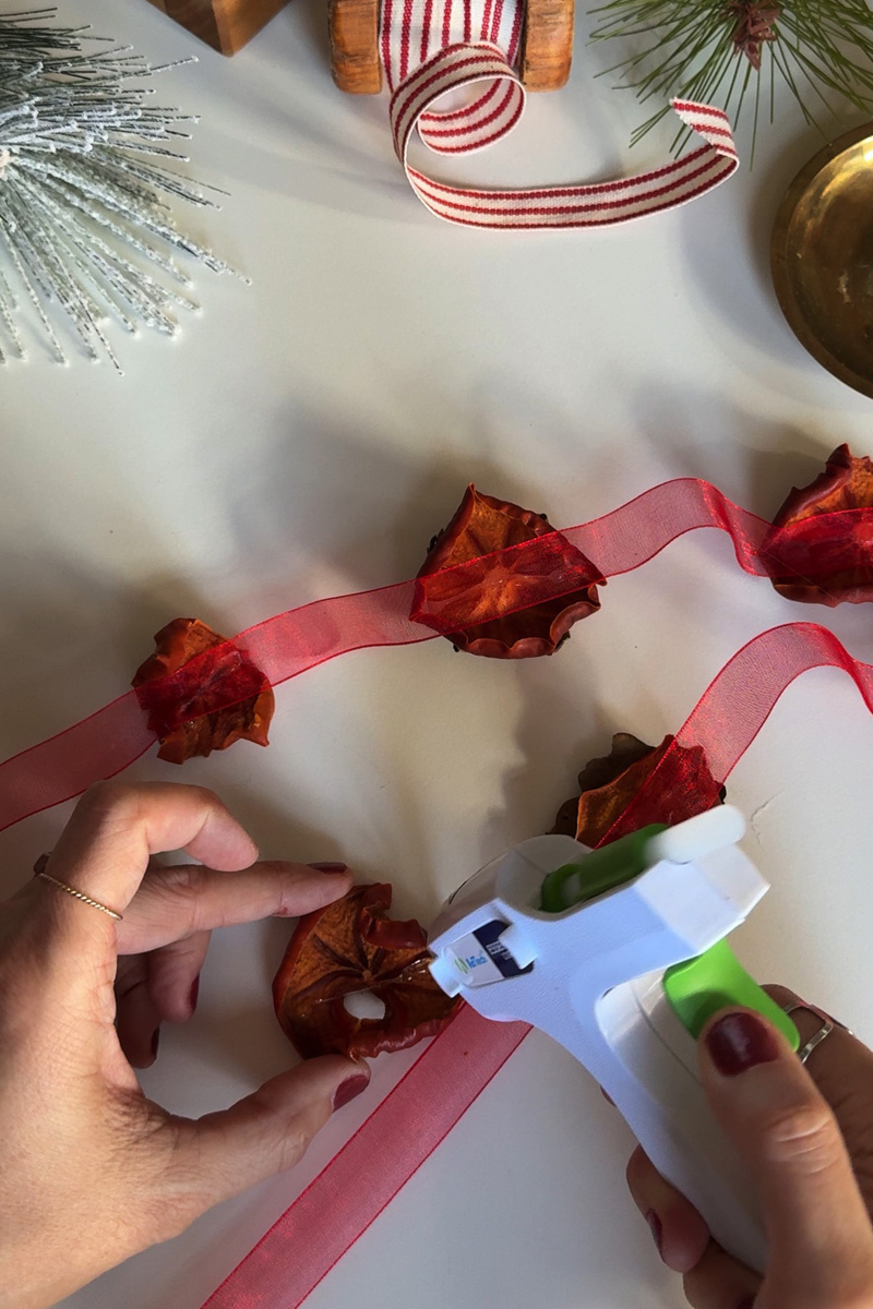 Gluing dried persimmon to a red ribbon