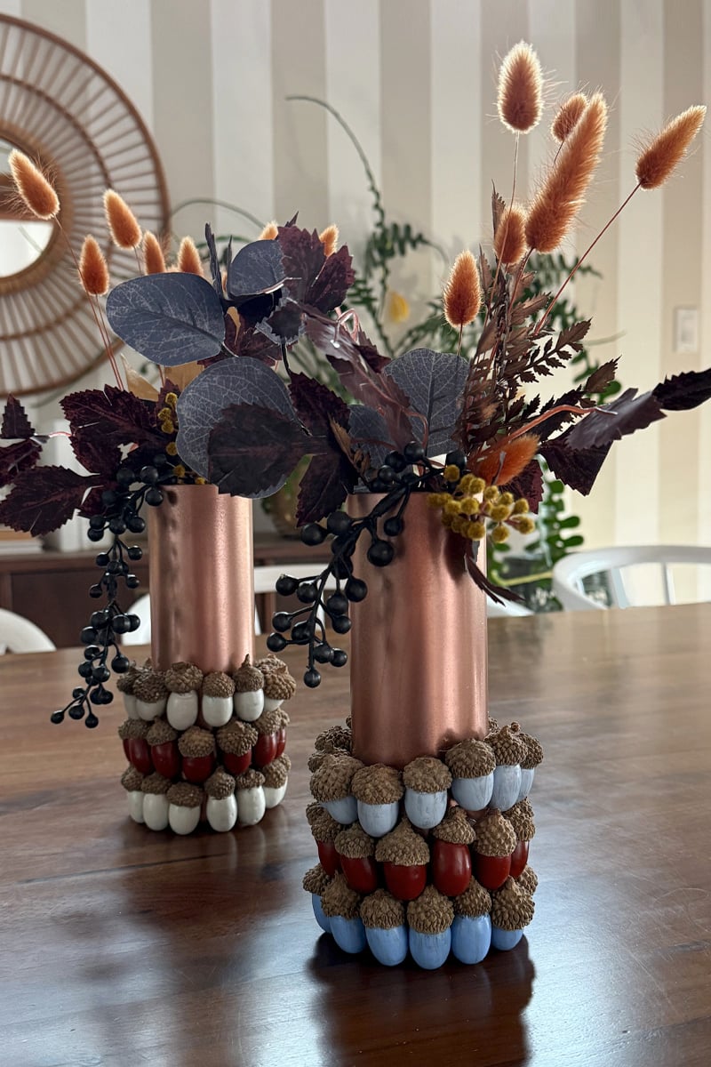 Colorful painted acorns on copper vase with Fall florals inside