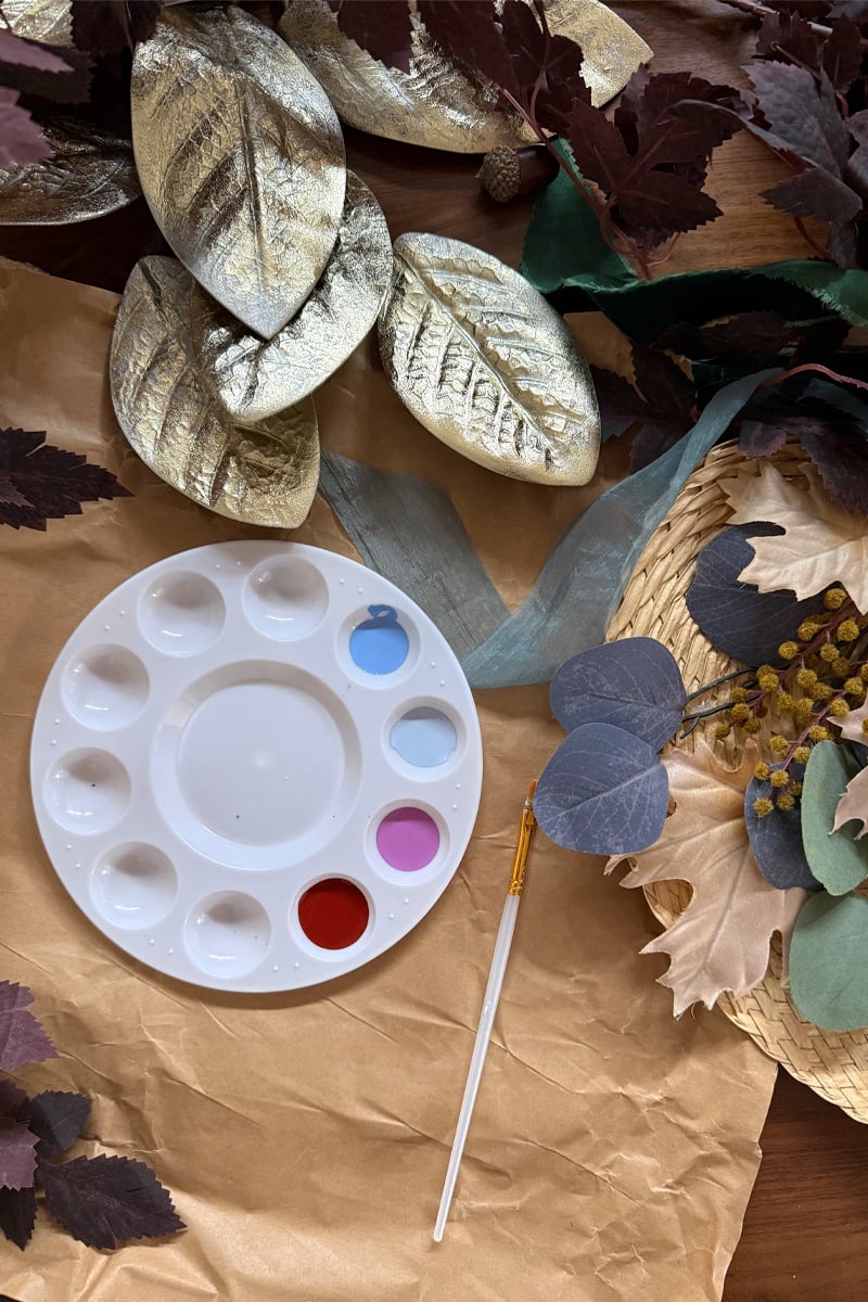 Paint palette against brown craft paper and fall leaves