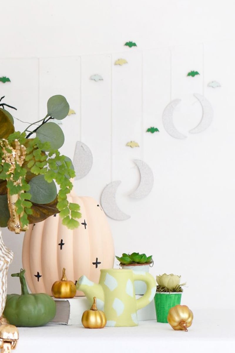Silver moon garland, watering cans and colorful mini pumpkin setup