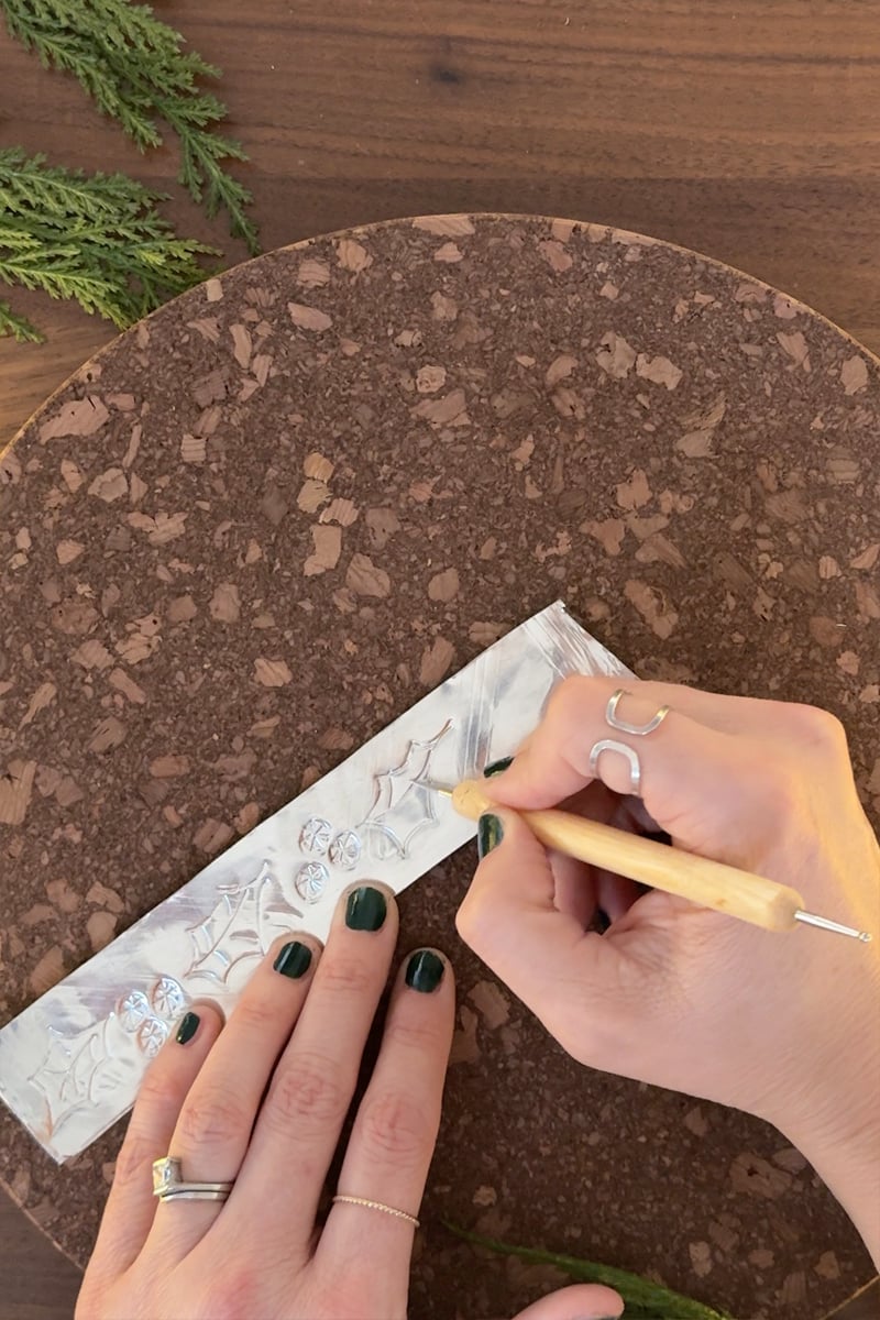 Embossing holly and berries onto silver metal strips