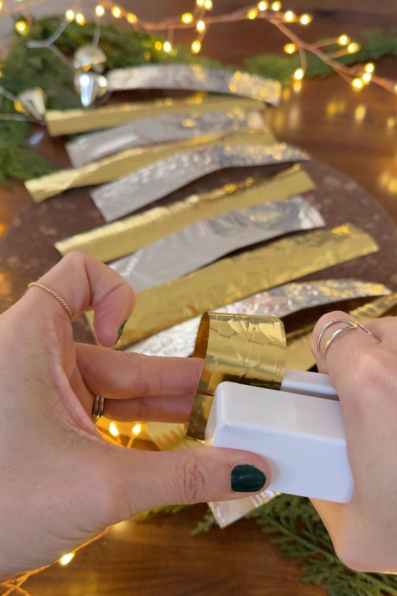 Using a white stapler to secure first gold metal chain garland