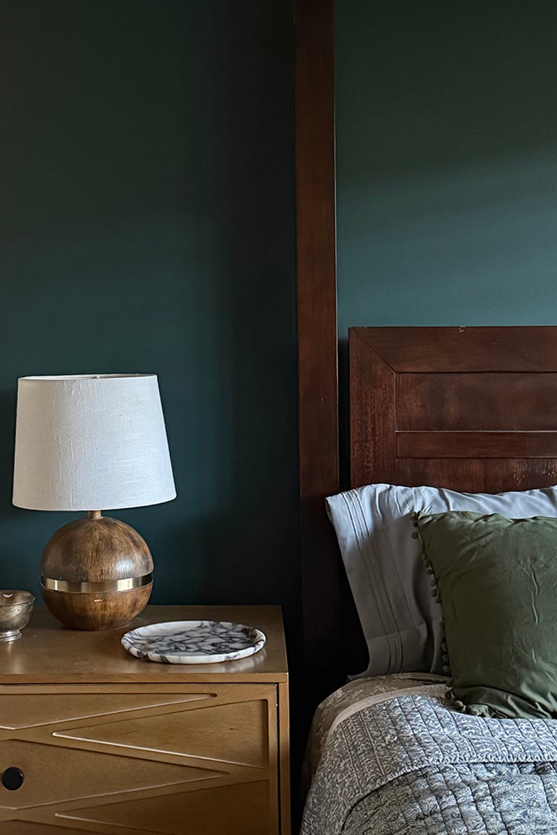 Dark green painted bedroom wall with darling night side table lamp