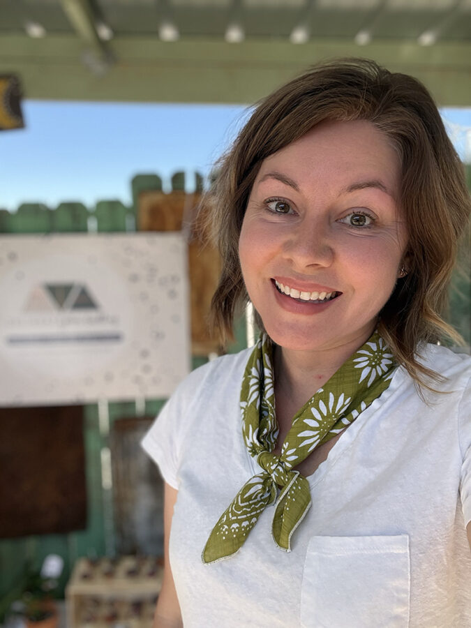 Vendor in green scarf full of cheer in booth