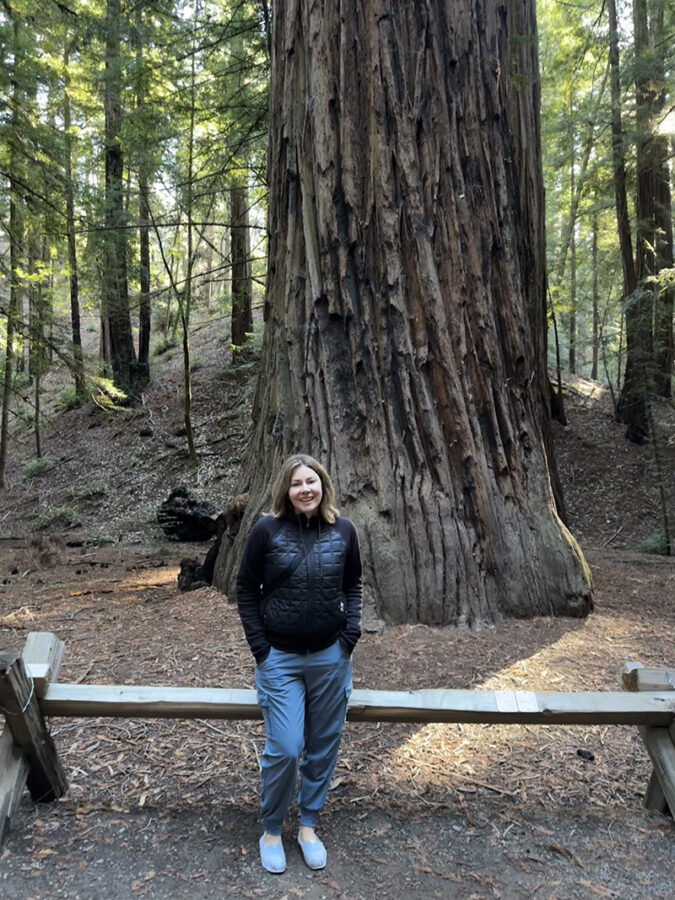 Woman standing near old Redwood tree in Armstrong Redwood Forest