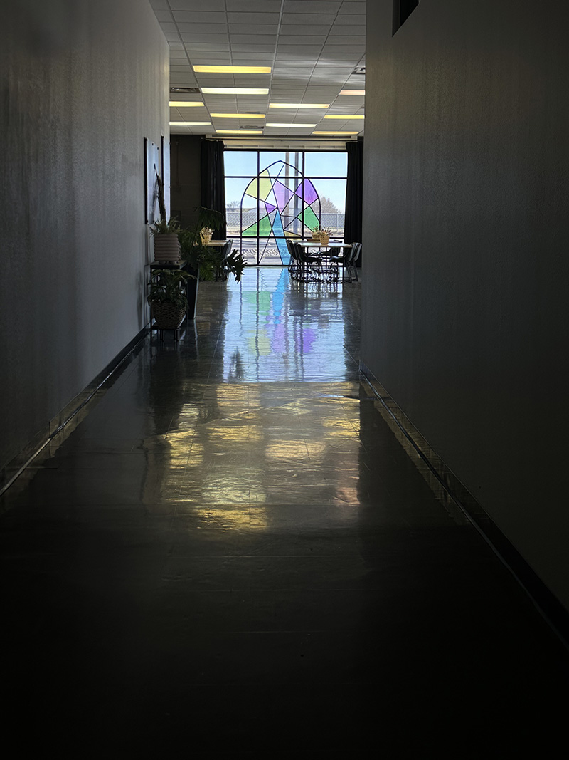 Dark hallway with colorful arched stained glass window