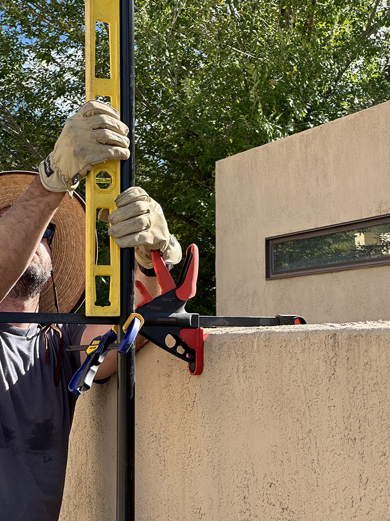 Leveling tall black pole against stucco wall