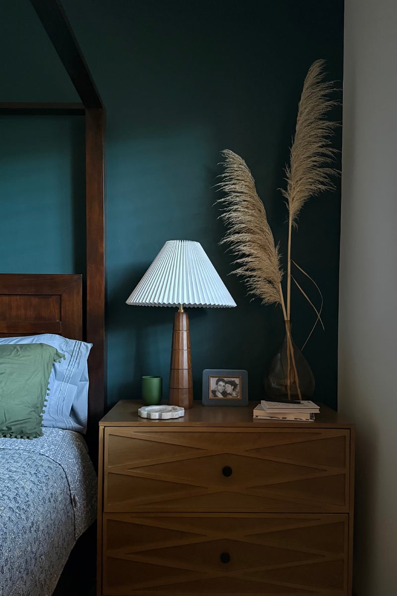 Dark moody bedroom with light brown oversized nightstand